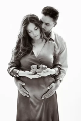 Photographe grossesse en Essonne pour une séance en couple en studio, mains posées sur le ventre