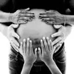 Mains de la famille sur le ventre, grossesse noir et blanc à Vert-Saint-Denis (77)