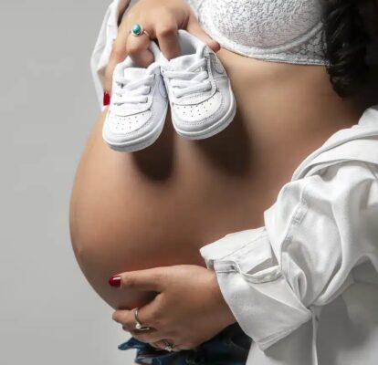 Photo de grossesse avec chaussons de bébé posés sur le ventre en Seine-et-Marne